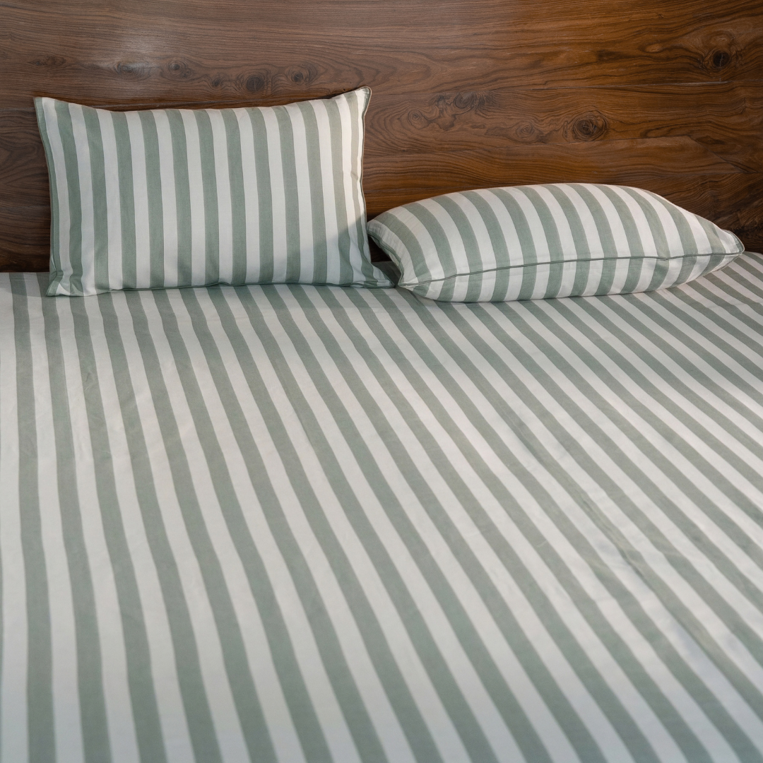 Pine Green yarn dyed stripe bedsheet set with two pillowcases against a walnut headboard