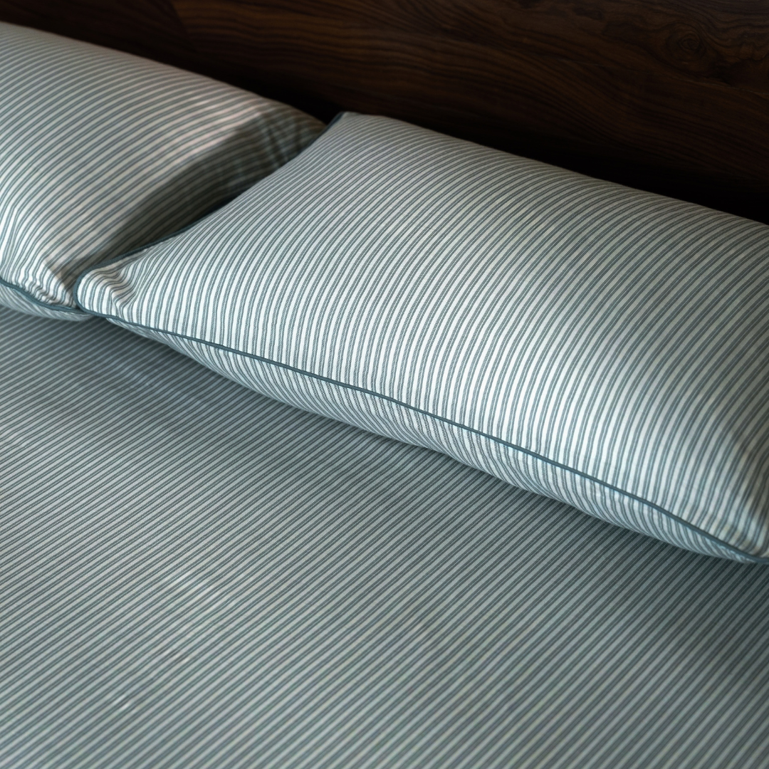 Close view of the pine green pin stripe pillow and fitted sheet in cotton percale