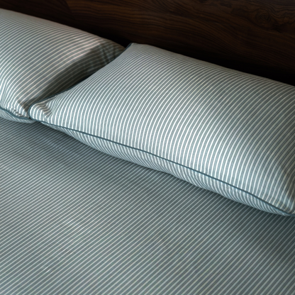 Close view of the pine green pin stripe pillow and fitted sheet in cotton percale