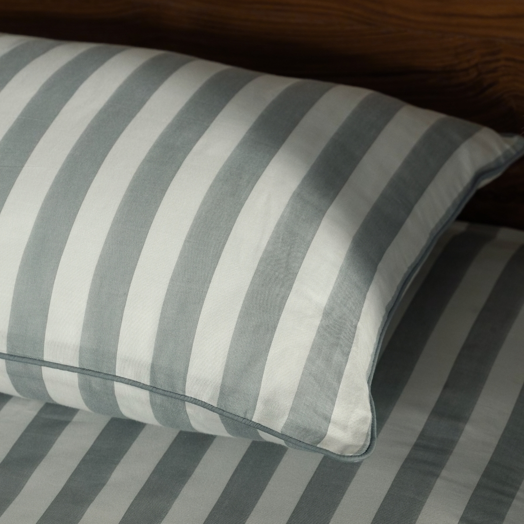 Close-up of a Pine Green striped pillowcase and its green piping on the matching sheet