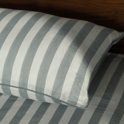 Close-up of a Pine Green striped pillowcase and its green piping on the matching sheet