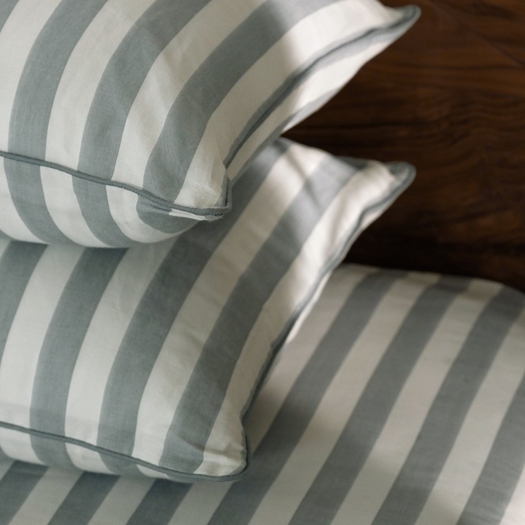 Stacked Pine Green striped pillowcases showing piped edges and soft sage yarn dyed stripes